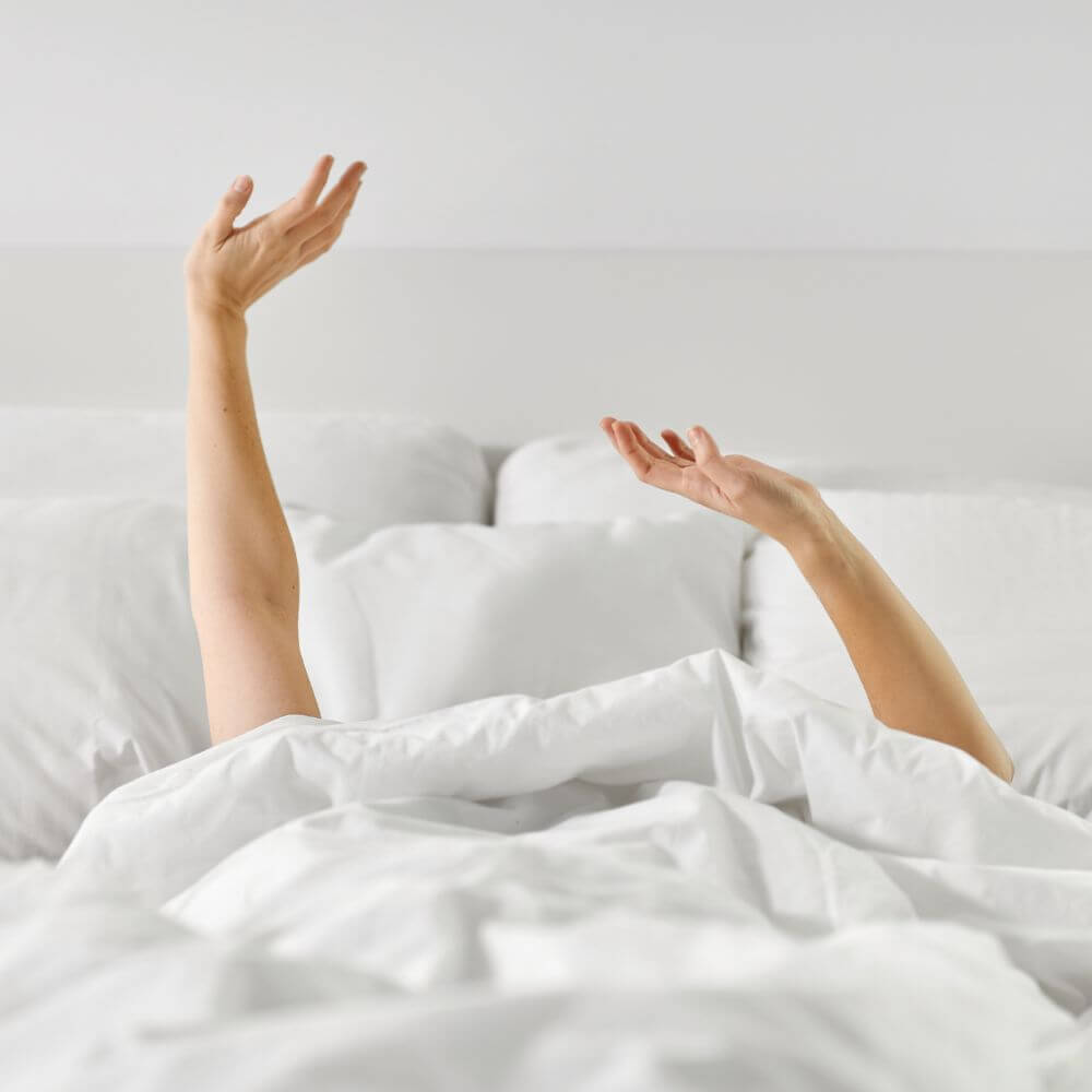 arms reaching out of blankets on bed
