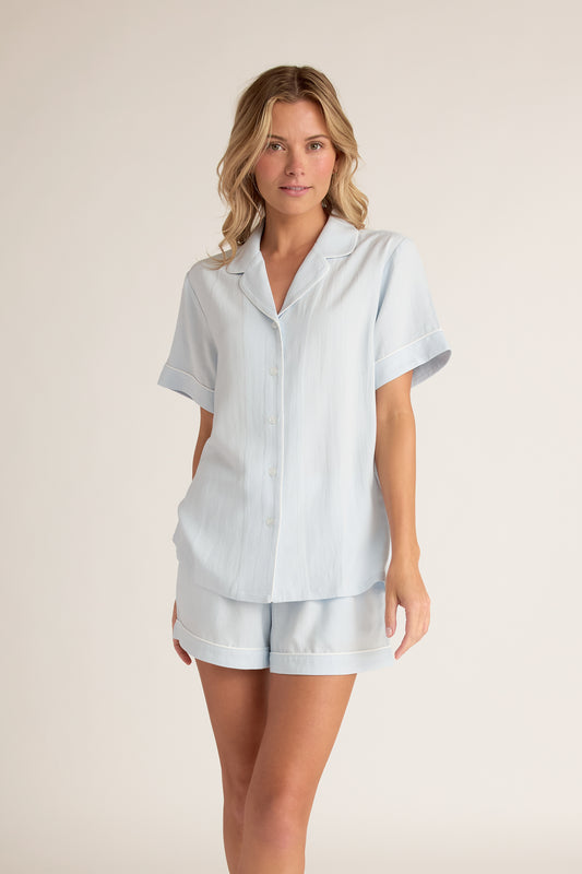 Woman wearing a light blue pajama set on a beige background